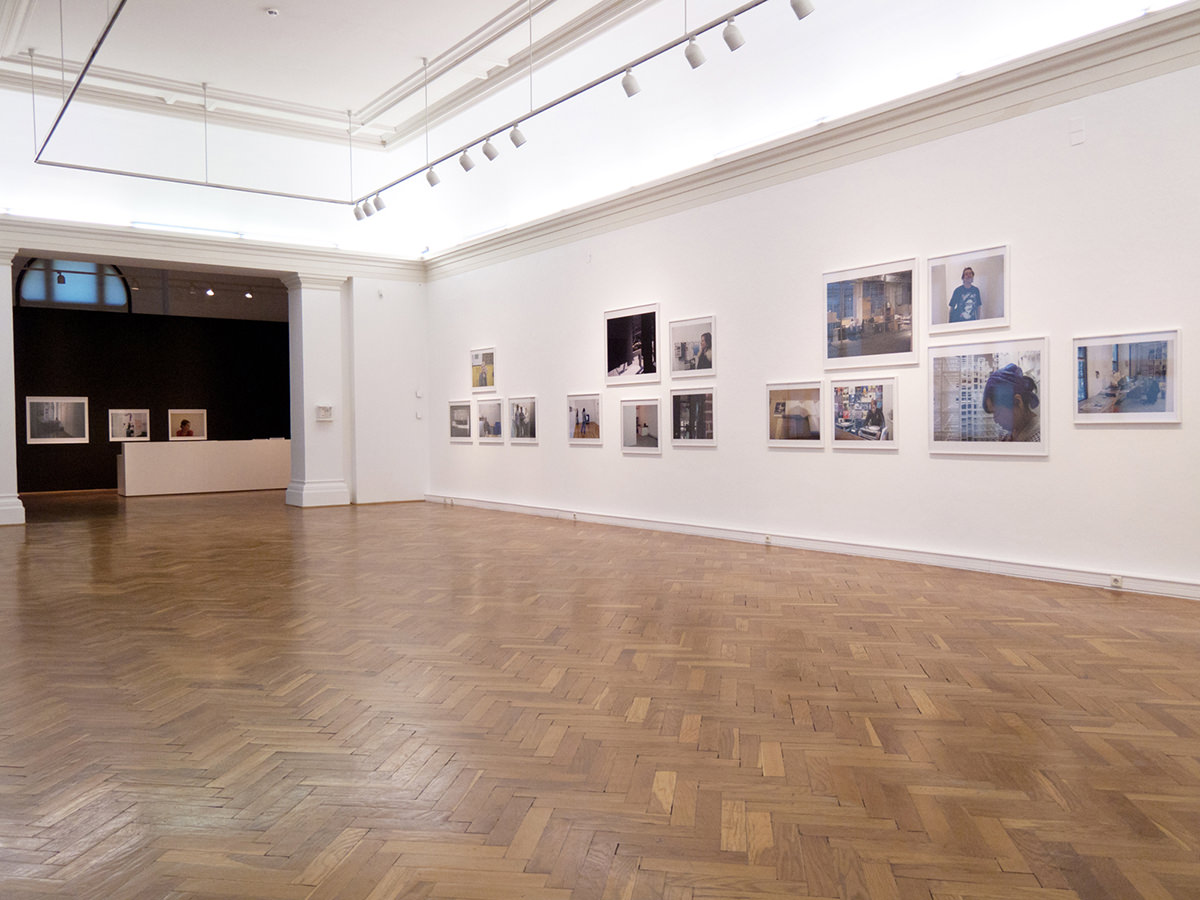 Ausstellungsraum mit Fotos an den Wändern und Holzboden
